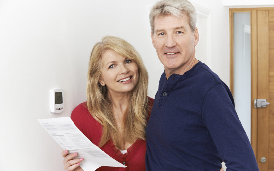 couple standing next to thermostat